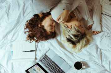 young women chilling on bed with laptop and coffee